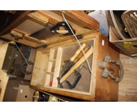 A wooden box with hand tools and horse brasses.