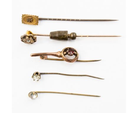 A diamond set gold stick pin, a 15ct gold stick pin, a garnet set stick pin and two others. (5)