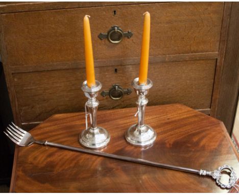 A pair of silver plated weighted candlesticks, together with a plated toasting fork, length of fork 62cm. (3)
