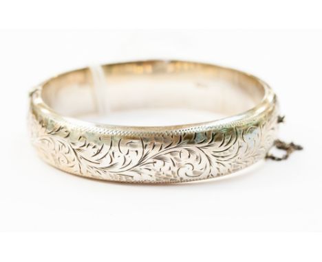 A silver hinged bangle engraved floral and scroll decoration, weighing 25.1 grams.