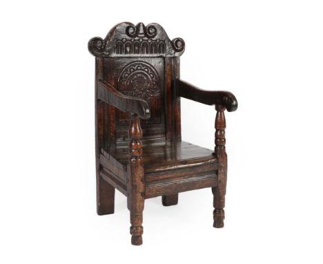 A Joined Oak Child's Chair, the nulled and scrolled top rail above a flower carved and crescent shape back support above a bo
