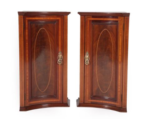 A Pair of Edwardian Mahogany and Satinwood Banded Pedestal Cupboards, early 20th century, of convex shaped form, the moulded 