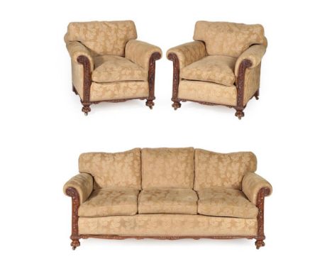 A Carved Mahogany Three Piece Suite, circa 1920/30, recovered in gold floral fabric, comprising a three-seater sofa with squa