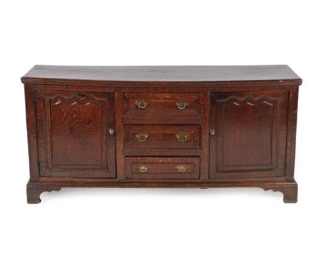 An Early 18th Century Oak Enclosed Dresser Base, the moulded edge above a bank of three drawers flanked by moulded cupboard d