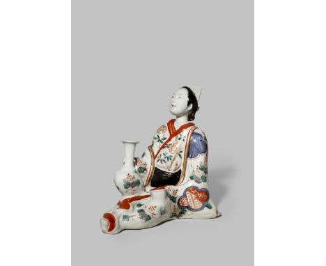 A RARE JAPANESE IMARI FIGURE OF A RECLINING BIJIN C. 1700 Painted in coloured enamels and gilt, the beauty rests on one hand 