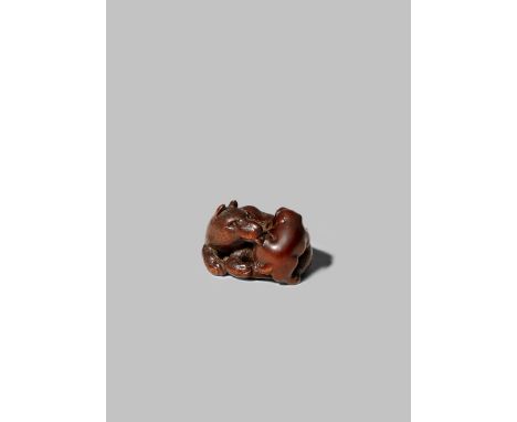 A JAPANESE WOOD NETSUKE EDO 1868-1912 Depicting a lying dog licking a small puppy climbing upon her back, signed Kokei undern
