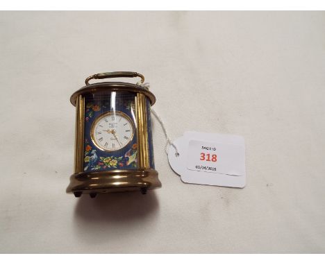 A Halcyon Days enamel decorated miniature oval carriage clock