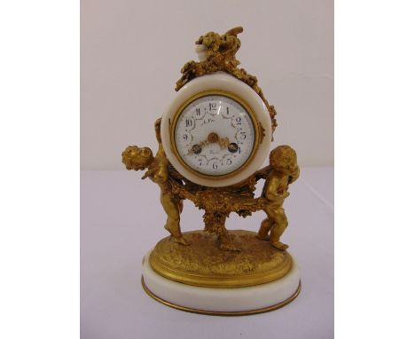 A French mantle clock of circular form, the white enamel dial with Arabic numerals supported by two putti on an oval ormolu a