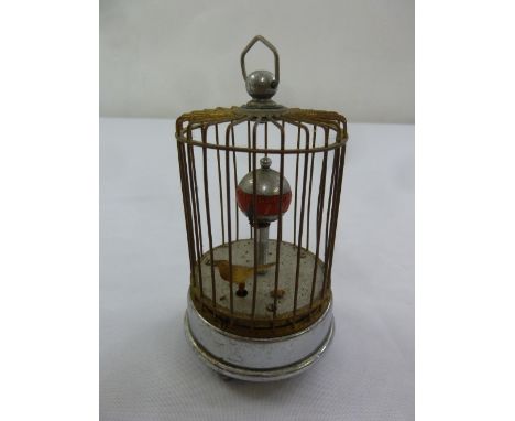 An automaton clock with bird in a cage with carrying handle on circular base