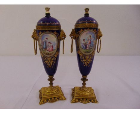 A pair of continental blue ceramic garnitures, the side oval panels decorated with figures, flowers, insects and leaves with 