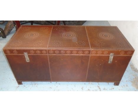 TRUNK, in a burnt umber leather with metal stud work, internal finish of painted wood with retaining straps on hinged rising 
