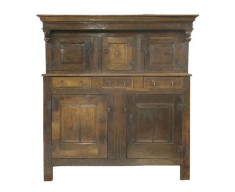 An oak court cupboard,with a moulded cornice over three panelled cupboards, the central cupboard enclosing a single shelf, ov