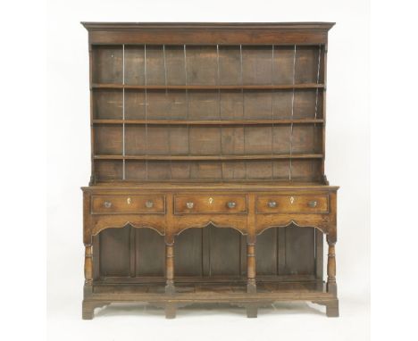 A George III oak dresser,the boarded three-shelf rack over three drawers with brass knob handles, over a shaped apron and pan