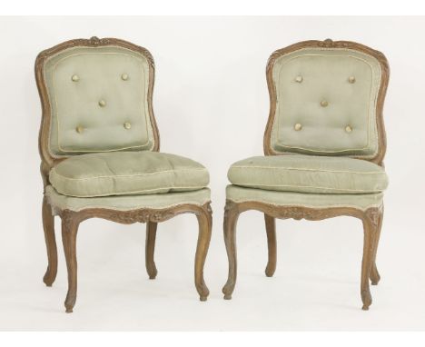 A pair of late 19th century Louis XV style beechwood single chairs, each with a button upholstered back on flower carved cabr