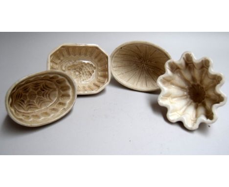 A set of four vintage ceramic jelly moulds, with patterns including a bunch of grapes and a spiderweb