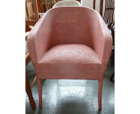 A pink Lloyd Loom style wicker armchair