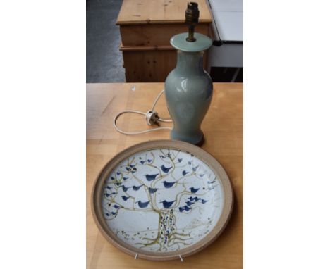 A decorative studio pottery plate painted with an abstract scene of blue birds in a tree, together with a green ceramic balus