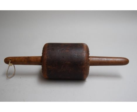 An antique C Schamutz rolling pin, the body covered in leather and with wooden handles