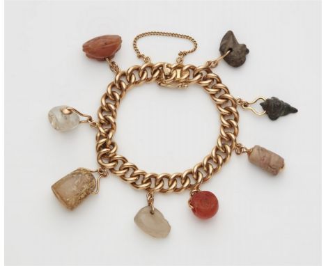 18 kt Rotgold. Hohles Band im Rundpanzermuster mit acht Anhängern. 1) Stein-Amulett in Vogelform, 1. Jahrtausend v. Chr., H 1