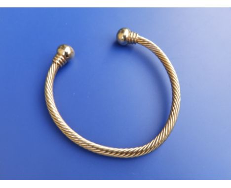 A yellow metal torque style bangle.