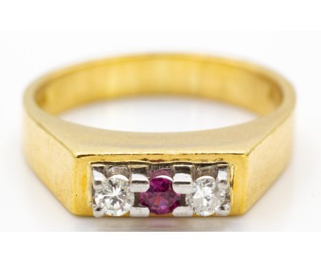 A hallmarked 18ct ruby and diamond three stone ring. The ring set with a central ruby flanked by two diamonds, estimated diam