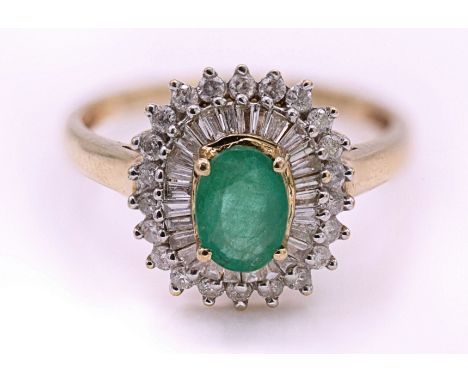 An 18ct gold emerald and diamond cluster ring. The ring with central emerald cabochon within a halo of baguette and round cut