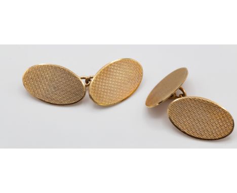 A pair of cased hallmarked 9ct gold cufflinks. The cufflinks of oval form with engine turned decoration united by chain link.