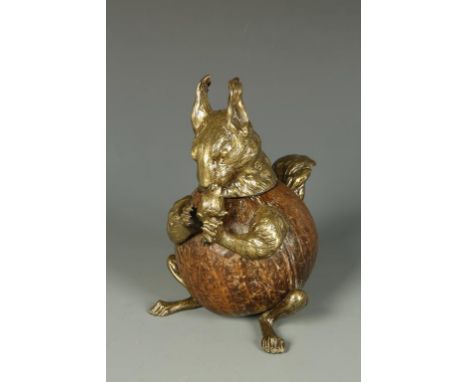 A LATE VICTORIAN OR EDWARDIAN SQUIRREL-FROM INKWELL, the body a polished coconut shell with brass mounts, the squirrel holdin