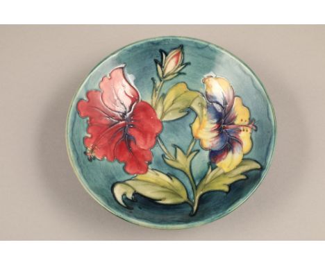 Moorcroft pottery footed bowl decorated with hibiscus design, on blue/green ground, signed, incised factory marks with origin