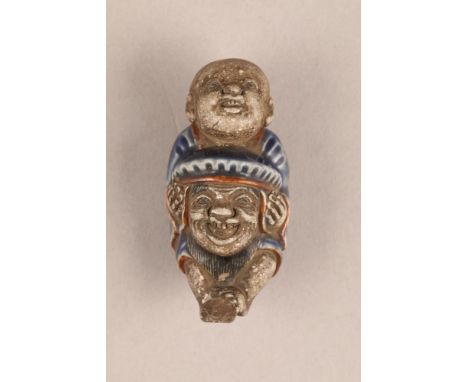 Japanese porcelain netsuke, modelled as a boy on his fathers shoulders, blue enamel, 6.3cm high.