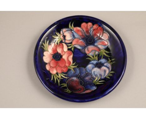 Moorcroft pottery dish, decorated in anemone design, on blue ground, signed William Moorcroft, incised factory mark to base, 