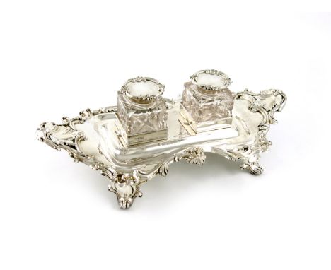 An Edwardian silver inkstand, by Mappin and Webb, London 1906, shaped rectangular form, shell and scroll border, on four heav