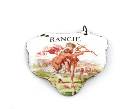 A rare mid 18th century Battersea enamel wine label, circa 1755, escutcheon form, with a wrestling cupid and satyr in a lands