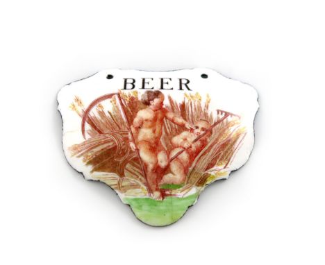 A rare mid 18th century Battersea enamel wine label, circa 1755, escutcheon form, with two cupids in a wheat field holding a 