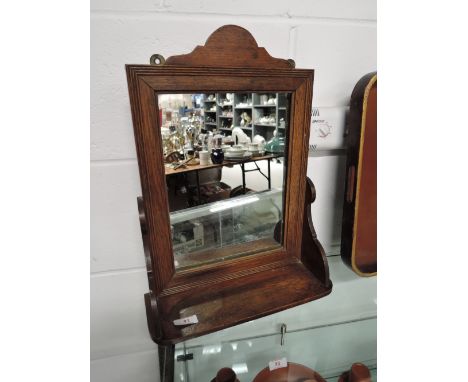 A vintage wall mounted mirror with integral shelf