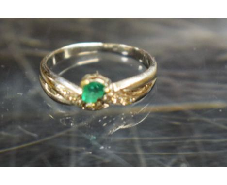 An emerald and diamond ring, heart shaped emerald trilliant set above seven round brilliant cut diamonds, 18ct white gold sha