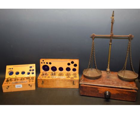 A set of apothecary scales mounted on single mahogany drawer, early 20th century; two later cased sets of weights in grams