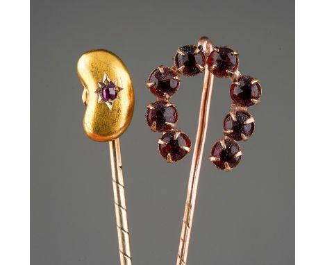 Two tie pins to include a 15 ct bean shaped one set with a ruby chip and a yellow metal horse shoe one set with 8 red stones