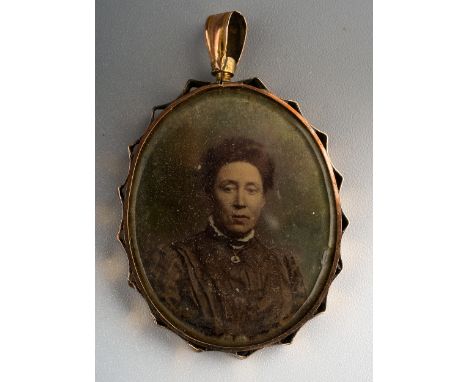 An early 20th Century yellow metal pendant complete with sepia portrait photographs of WWI Cavalry trooper and his mother