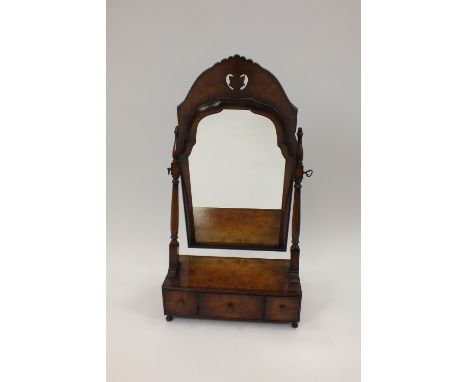 A 19th century walnut swing toilet mirror, the arched plate with ogee surround supported by twin turned pillars, the base hav