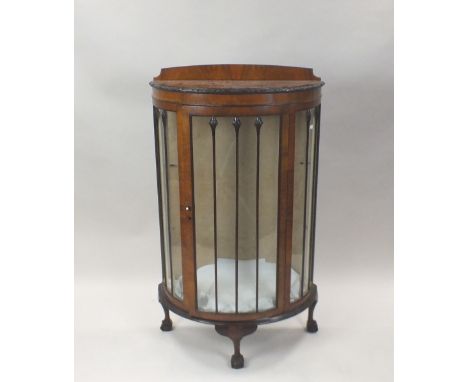 A 1930s walnut veneered bow front display cabinet on three squat cabriole legs and claw and ball feet, 76cm wide, 37cm deep, 