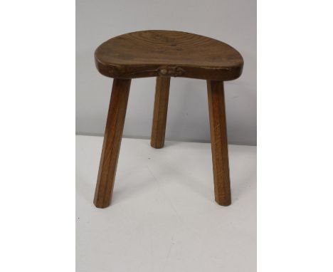 A vintage Robert 'Mouseman' Thompson of Kilburn milking stool with three legs and kidney shaped seat. With carved mouse on si