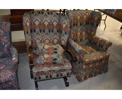 A vintage wingback rocking chair having William Morris style covers and a similar wingback armchair