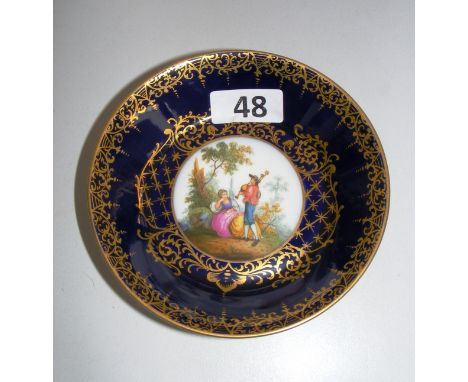 A Vienna saucer with a central painted scene against a gilt and cobalt ground. 