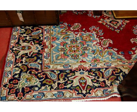 A Persian woollen Tabriz type carpet, the red ground having a central medallion issuing flowers and foliage within trailing t