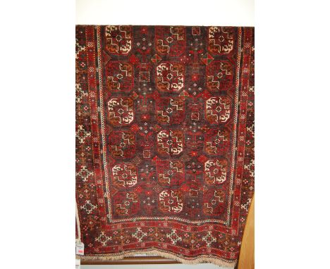 A semi-antique Persian woollen Bokhara carpet, decorated with three rows of octagonal medallions within trailing tramline bor