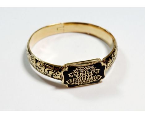 A Victorian black enamel and gold hinged bangle inset hair locket and inscribed 'Lady Henrietta Fergusson 1850', 25g, unmarke