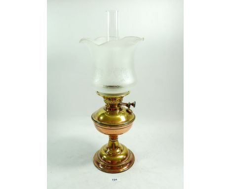 A Victorian oil lamp with etched glass shade and a copper and brass base
