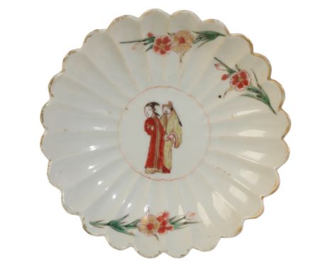 A CHRYSANTHEMUM PETAL SAUCER DISH Kangxi, painted in the Japanese Arita style, the centre with a yellow robed man standing be