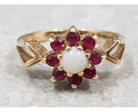 Ladies 9ct yellow gold ruby and opal cluster ring, comprising of a opal set in the centre surrounded by 8 red stones, all the